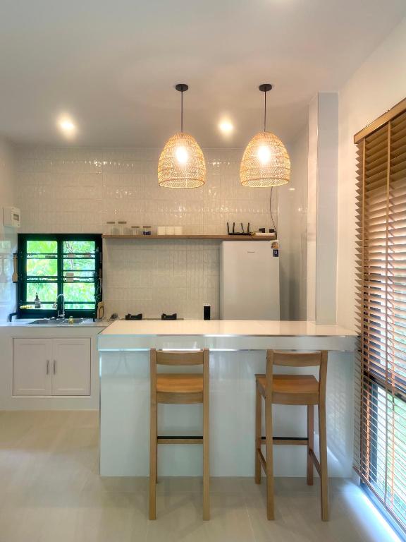 eine Küche mit zwei Barhockern und zwei Leuchten in der Unterkunft The Whispering Palm Coconut Lane in Ko Phangan