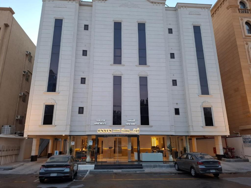 达曼ONSEN Hotel AL-SHATI أونيسن的两辆汽车停在一栋建筑前的停车场