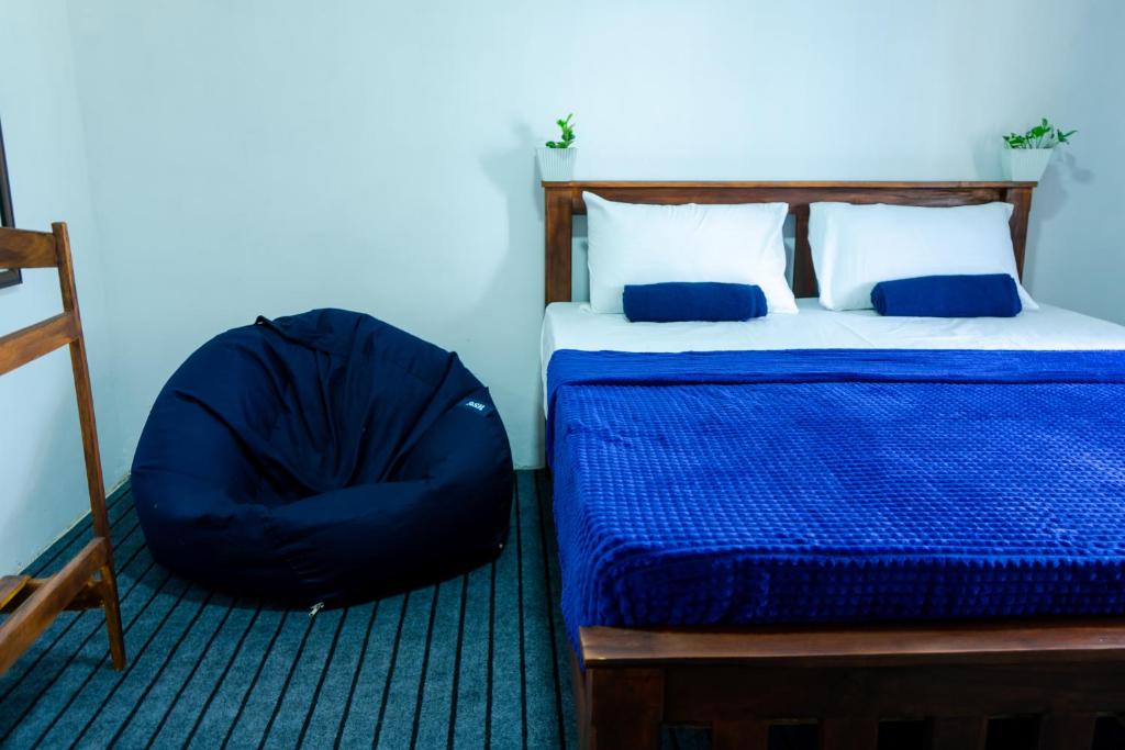 Un dormitorio con una cama con una manta azul y una silla. en Mountain Lodge, en Bandarawela