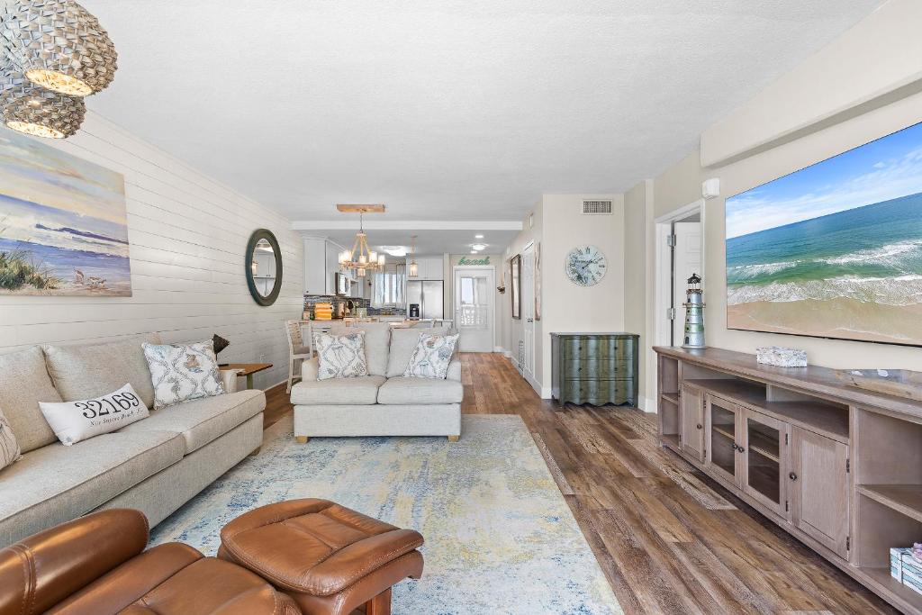 a living room with a couch and a tv at Golden Arms 602 in New Smyrna Beach