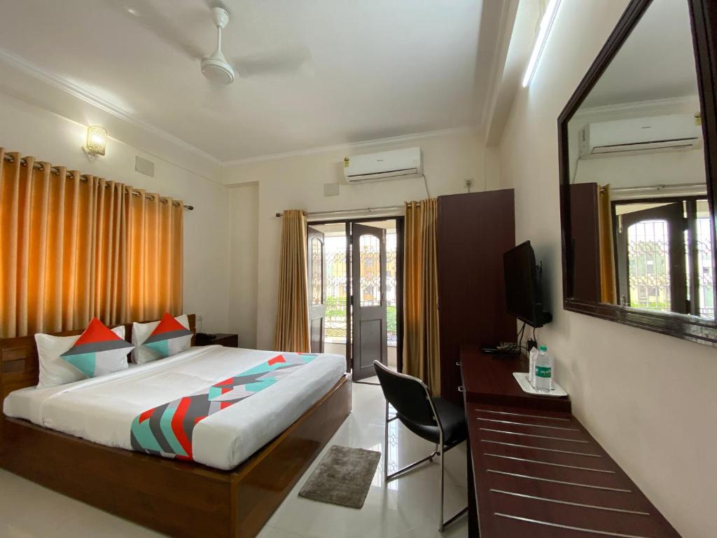 ein Schlafzimmer mit einem Bett, einem Schreibtisch und einem Fernseher in der Unterkunft Krishna Kunja " A Quiet & Peaceful Stay " in Kalkutta