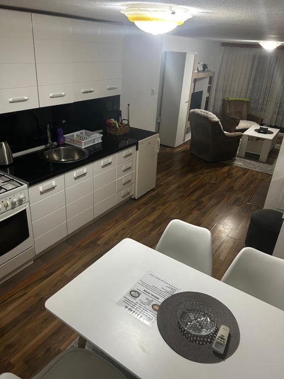 a kitchen with white cabinets and a table with chairs at Apartman MIA in Travnik