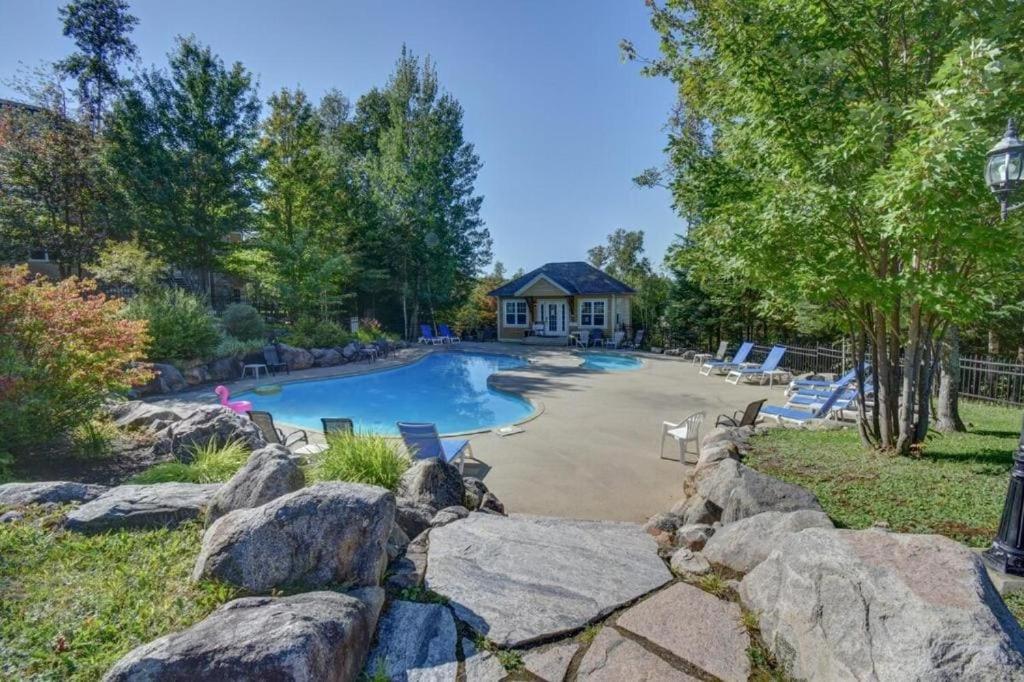 a swimming pool in a yard with rocks at Condo familial Mont Blanc, accès ski in Ski out in Saint-Faustin