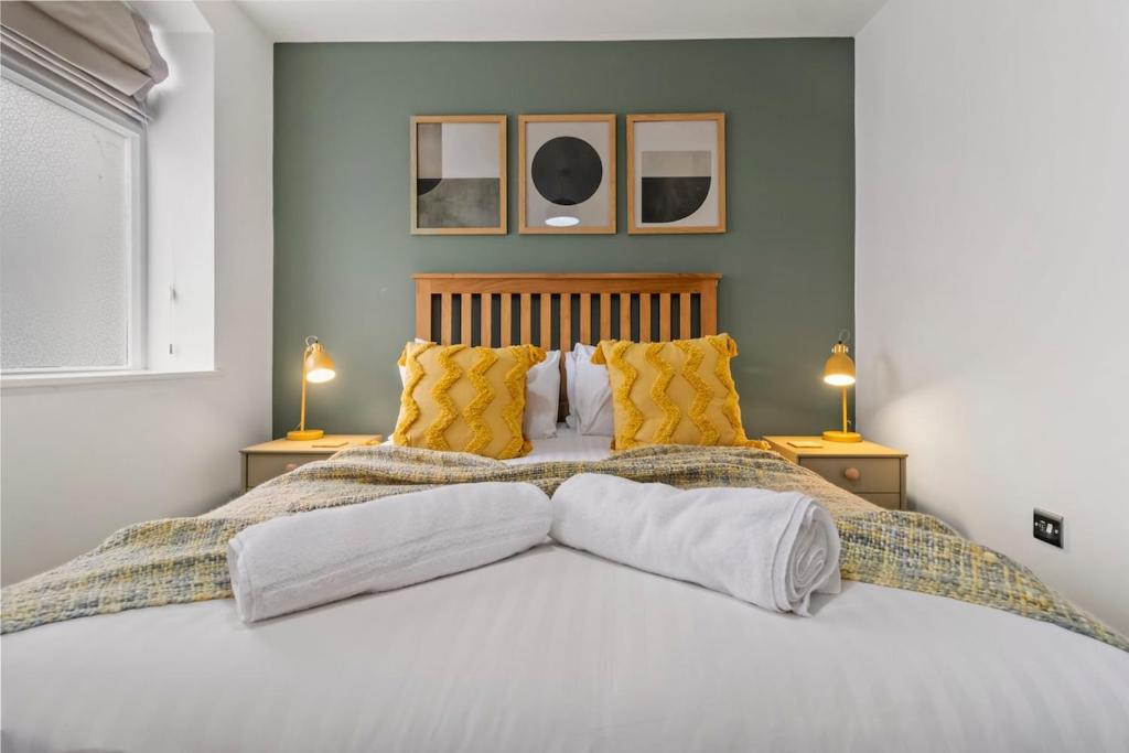 une chambre avec un grand lit avec des oreillers jaunes dans l'établissement Perry - Stylish City Centre Apartment, à Worcester