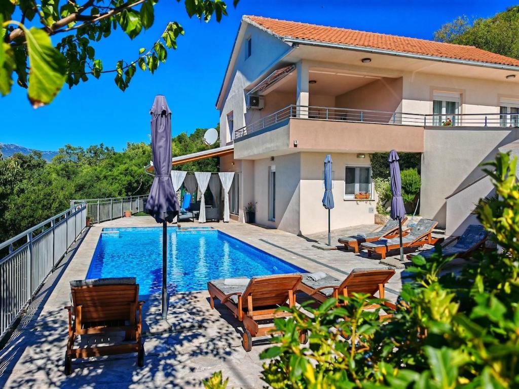 a swimming pool with chairs and umbrellas next to a house at Villa MAJIC SOL - Zavojane, Makarska region in Zavojane