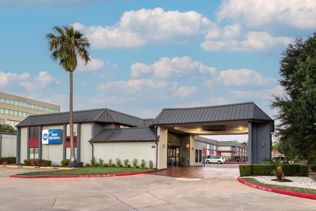 a building with a palm tree in front of it at Best Western Webster Hotel, NASA in Webster