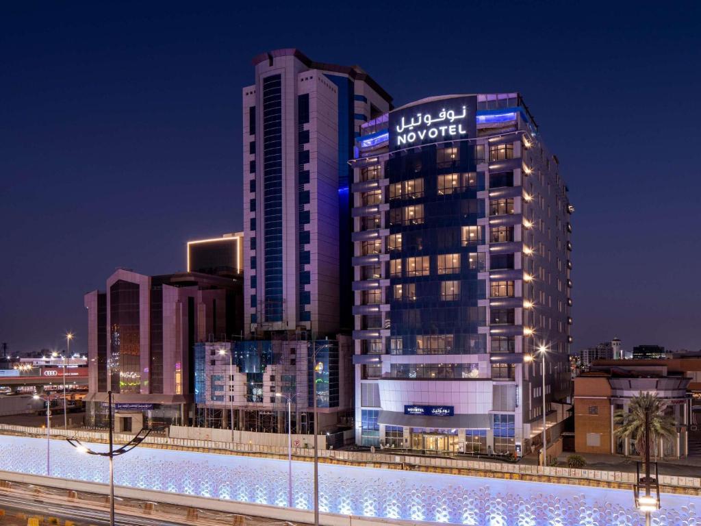 ジッダにあるNovotel Jeddah Tahliaの夜に看板が掲げられた高層ビル