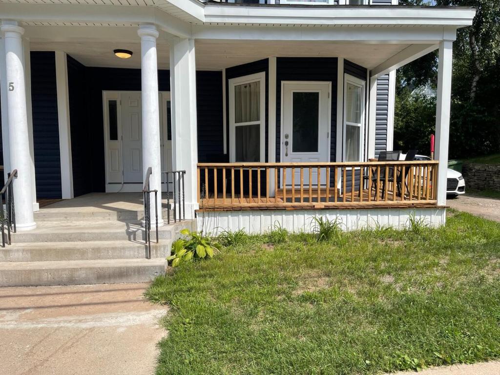 a house with a porch with a wooden deck at Wolfville Veranda Suite 1 Downtown Vibrancy in Wolfville