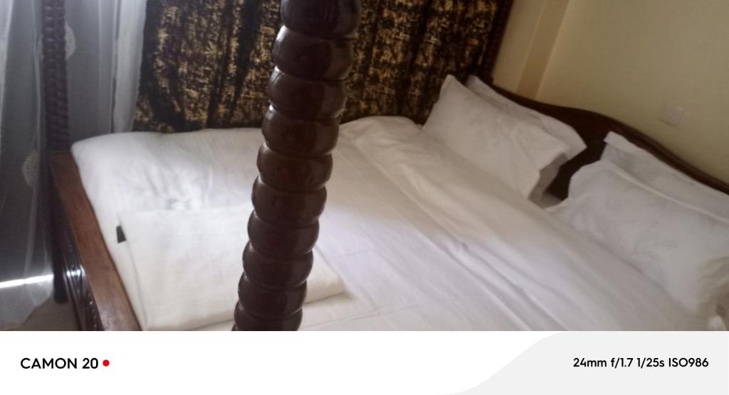 a bed with white sheets and a wooden post at Langata bnb in Nairobi