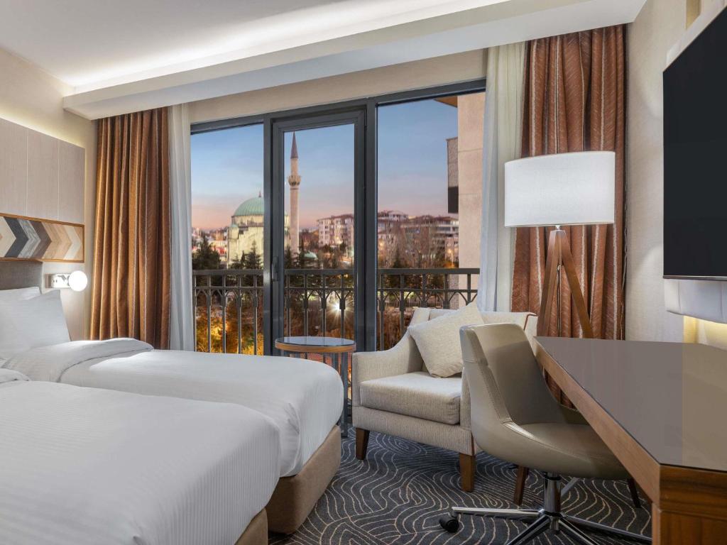 a hotel room with a bed and a desk and a window at Mercure Ankara Kızılay in Ankara