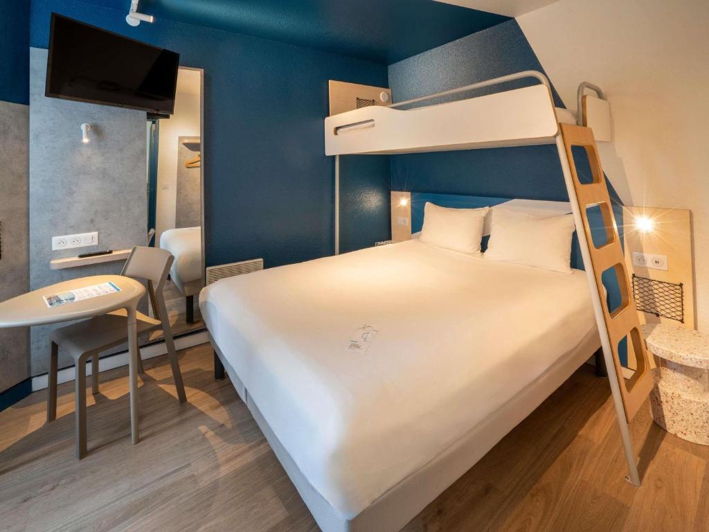 una camera da letto con un letto a castello e una scrivania di ibis budget Rennes Chantepie - Hôtel rénové a Chantepie