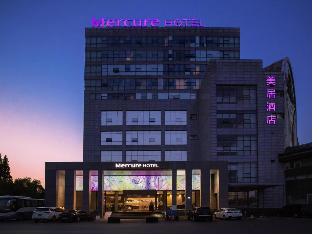 a moderne hotel with cars parked in front of it at Mercure Shanghai Hongqiao South in Shanghai