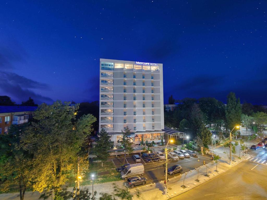 un edificio alto en un estacionamiento por la noche en Mercure Galati Centrum, en Galaţi