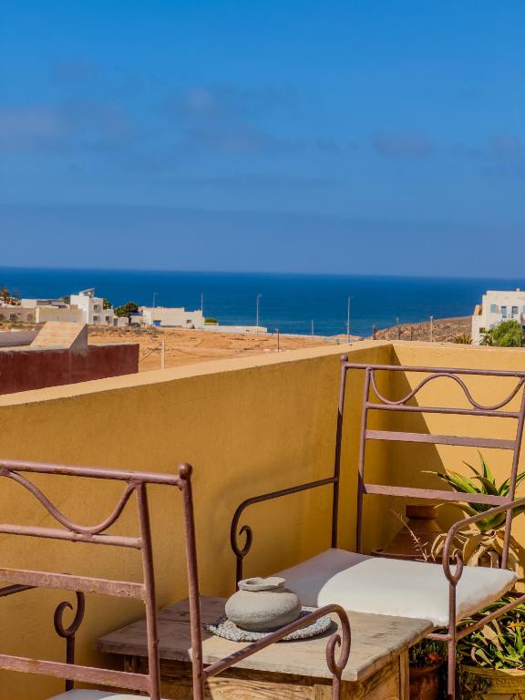 Ein Balkon mit zwei Stühlen und dem Meer im Hintergrund in der Unterkunft Tayafut Apartments & Terrace by Surfleft Morocco in Mirleft