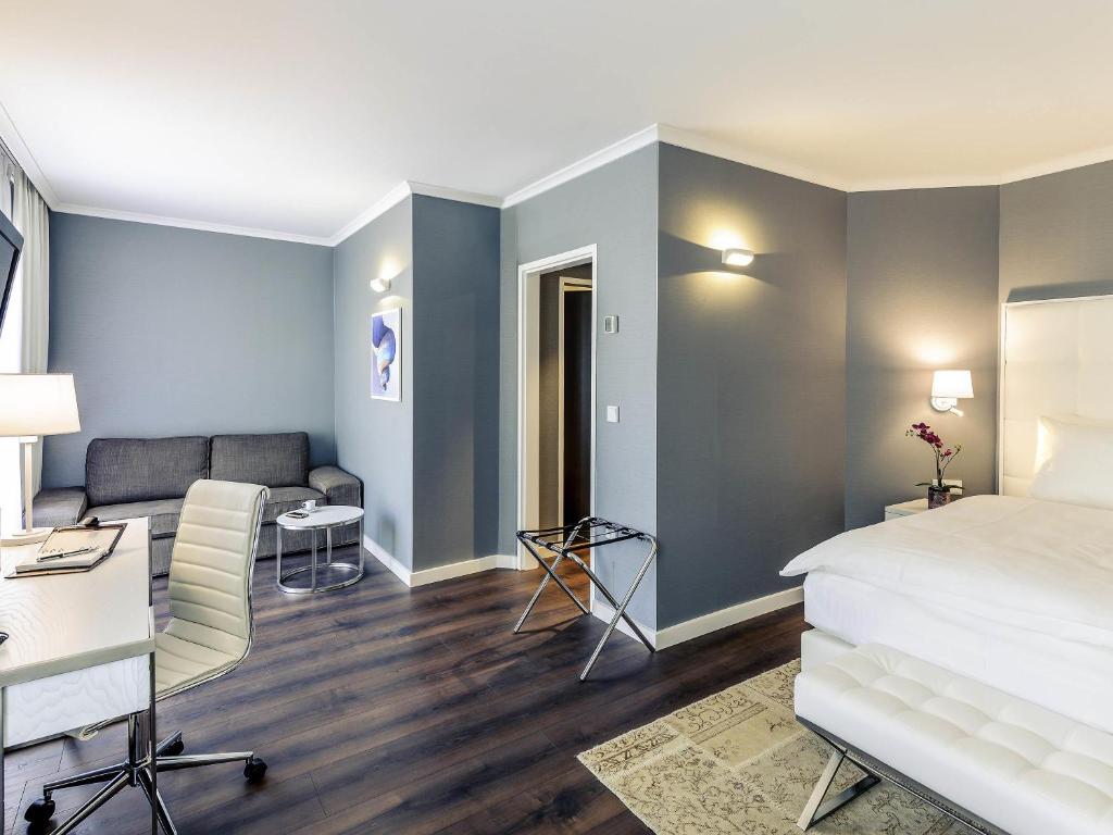 a bedroom with a bed and a desk and a couch at Mercure Hotel Raphael Wien in Vienna