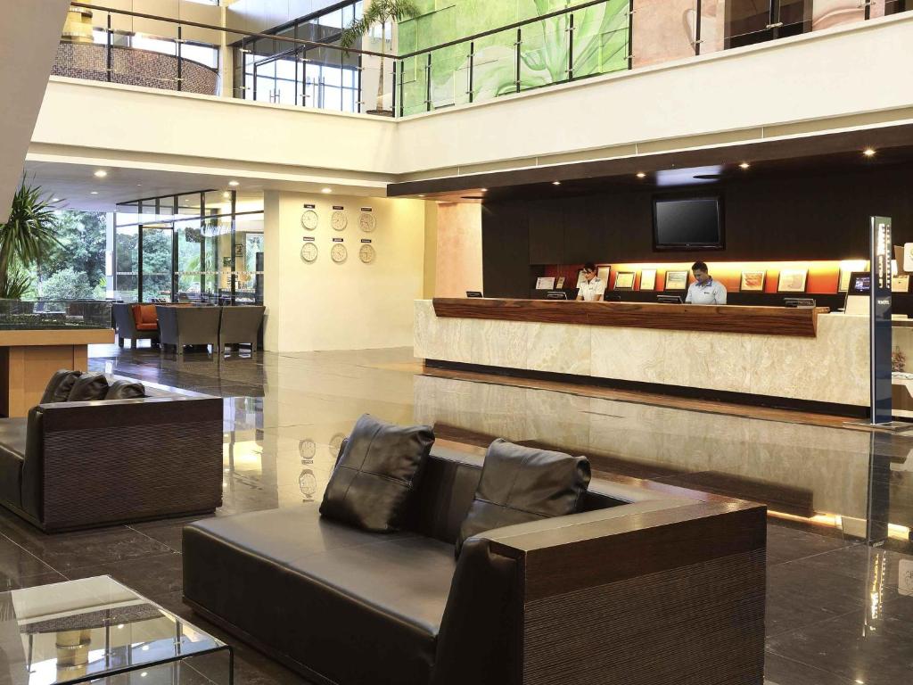 a lobby with couches and a tv in a building at Novotel Manado Golf Resort & Convention Center in Manado