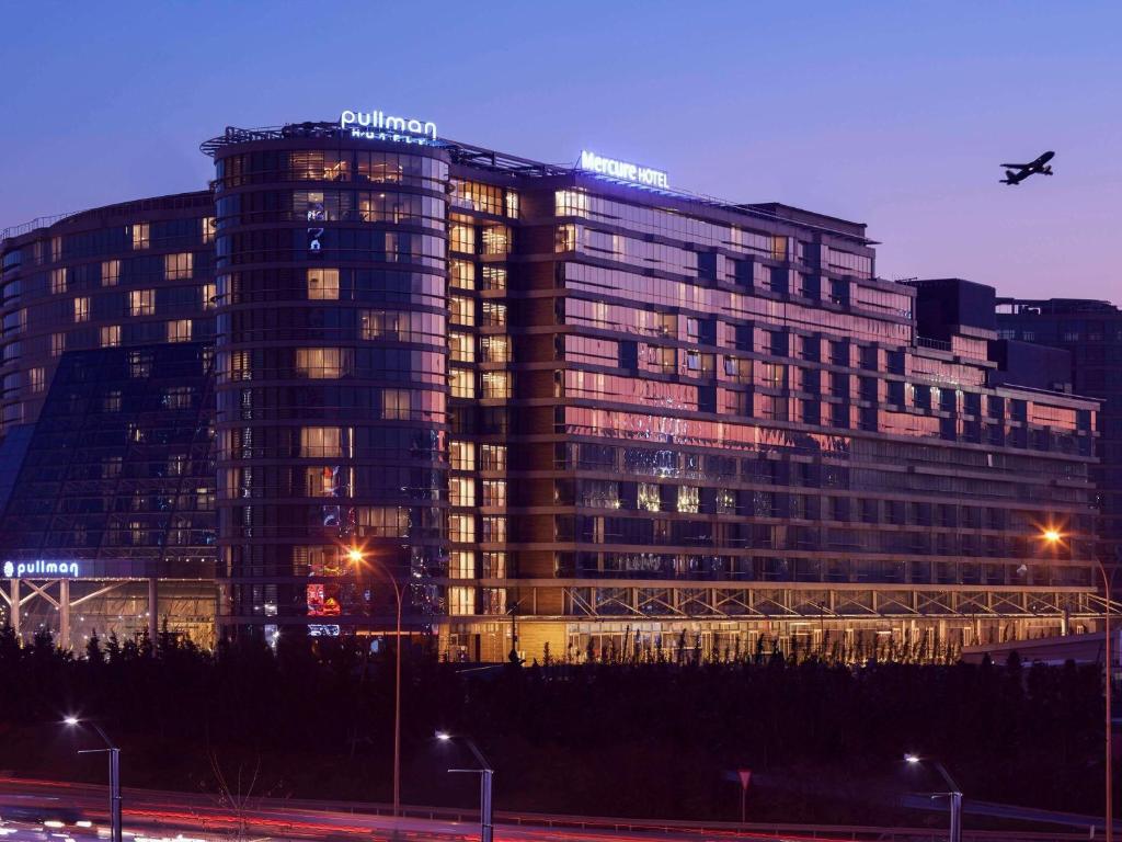 un gran edificio con un avión volando sobre él en Pullman Istanbul Hotel & Convention Center, en Estambul