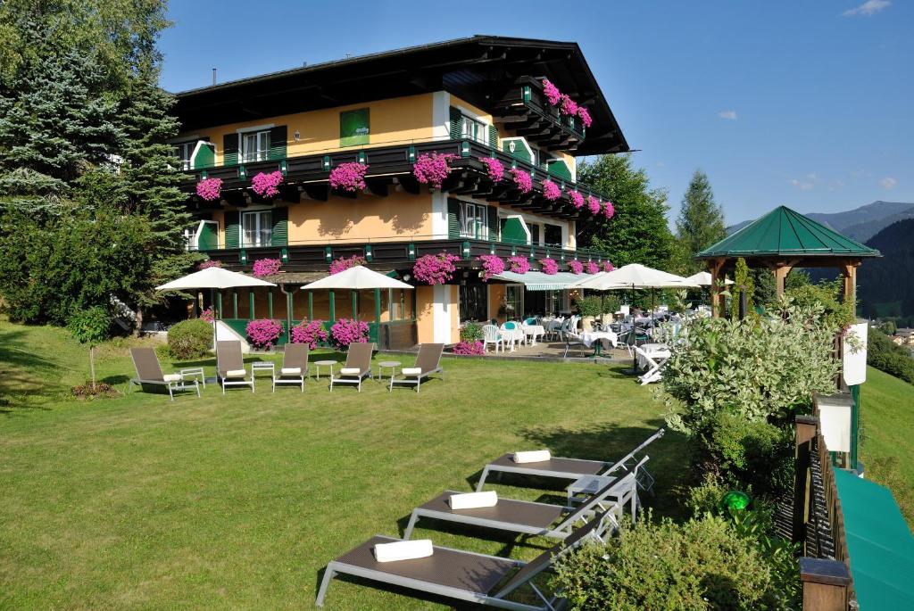 un hôtel avec des tables et des chaises devant lui dans l'établissement eva,GARDEN, à Saalbach-Hinterglemm