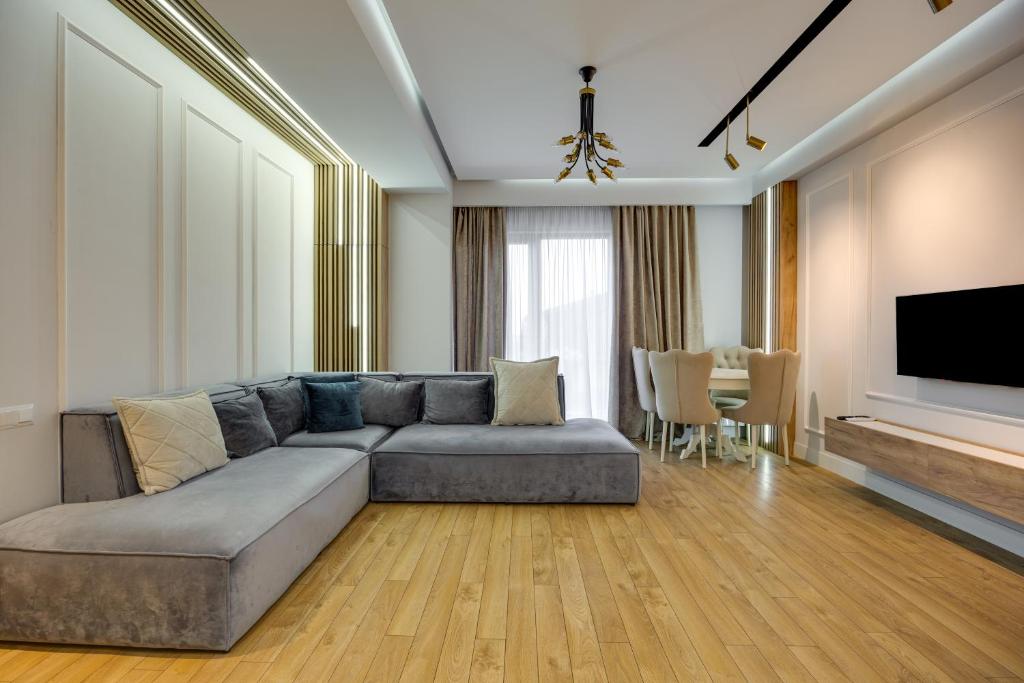a living room with a gray couch and a television at Hilton Blox Avlabari Apartment in Tbilisi City