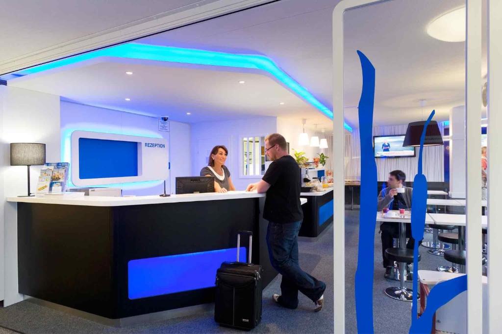 a man and a woman standing at a counter in an office at Ibis Budget Montbéliard in Montbéliard