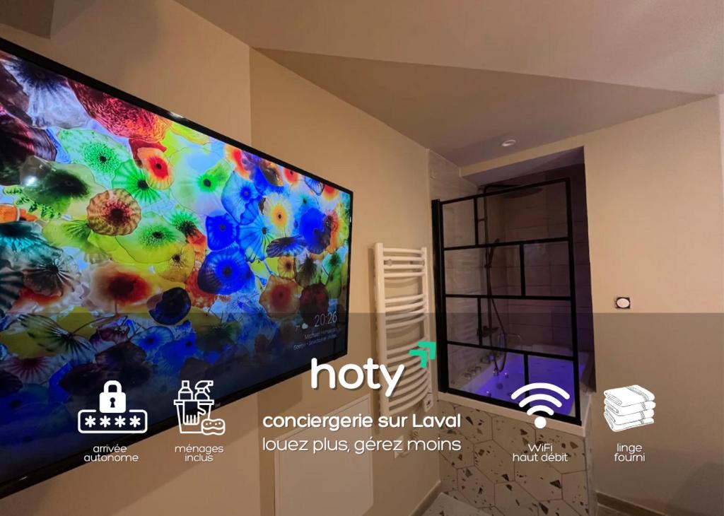 Un televisor de pantalla plana colgado en una pared en ESCAPADE Sereine - Studio Balnéo à Laval, en Laval