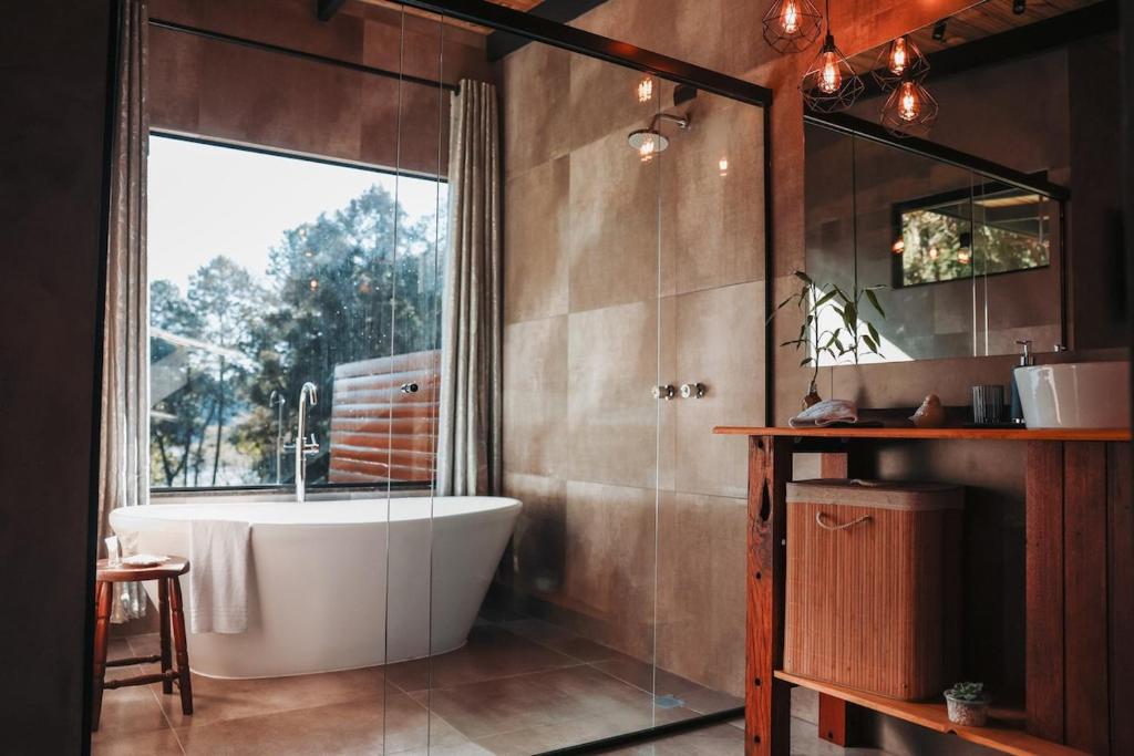 a bathroom with a bath tub and a window at Chalé Climatizado com banheira em frente ao Parque do Passaúna em Curitiba by Tiny House Passaúna in Curitiba