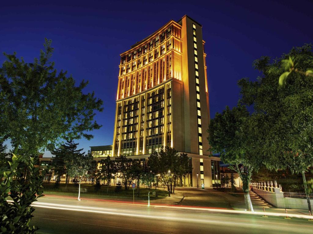 マラティヤにあるMovenpick Hotel Malatyaの高い建物は夜にライトアップされる