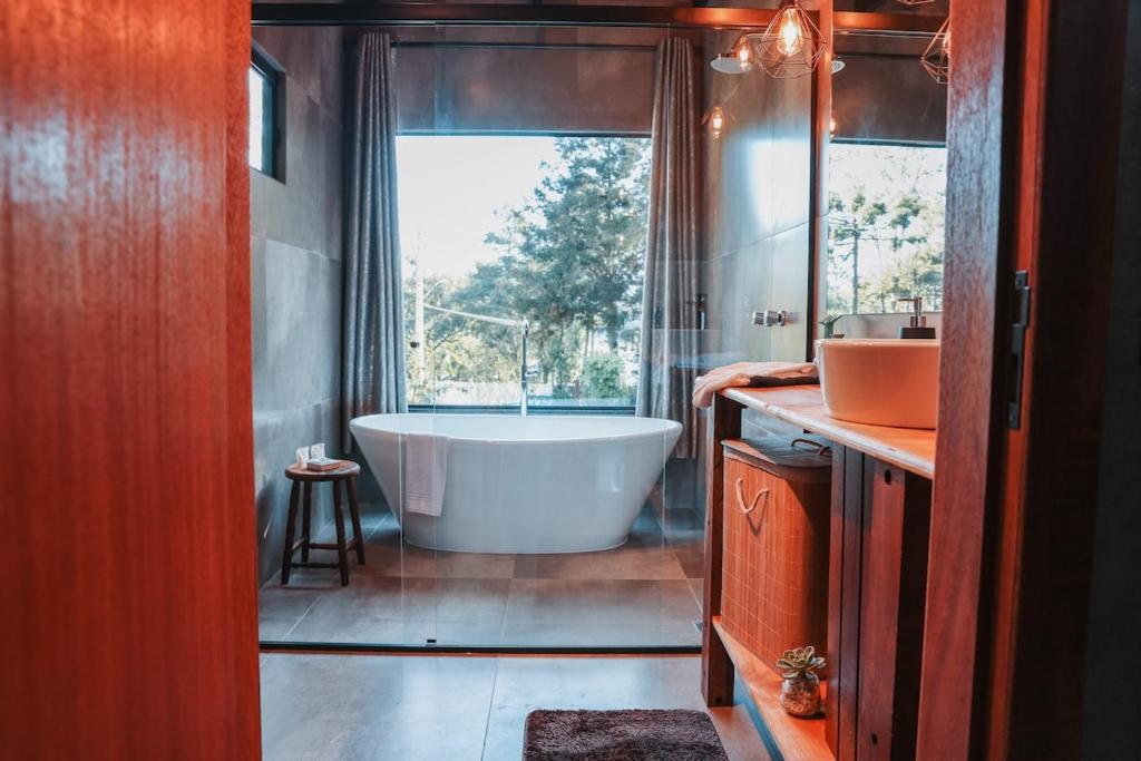 a bathroom with a tub and a large window at Chalé Climatizado, com banheira e varanda em frente ao Parque do Passaúna em Curitiba by Tiny House Passaúna in Curitiba
