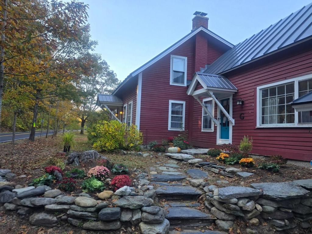 Una casa roja con un camino de piedras al frente. en The Cardinal Lodge- A Riverside Retreat, en Newfane