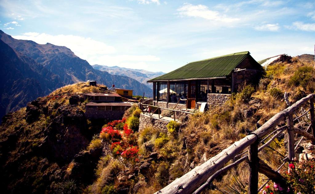 un bâtiment sur le côté d'une montagne avec des fleurs dans l'établissement La Granja del Colca, à Cabanaconde