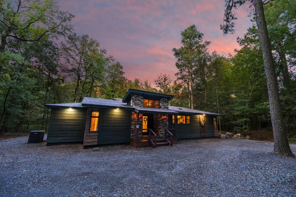 a small cabin in the woods at dusk at Wine Time 5 Bedroom Shuffleboard Hot Tub Fire Pit Play Set in Broken Bow