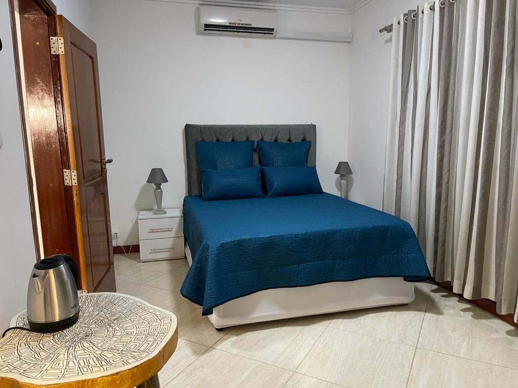 a bedroom with a blue bed and a table at AK Guesthouse in Maputo