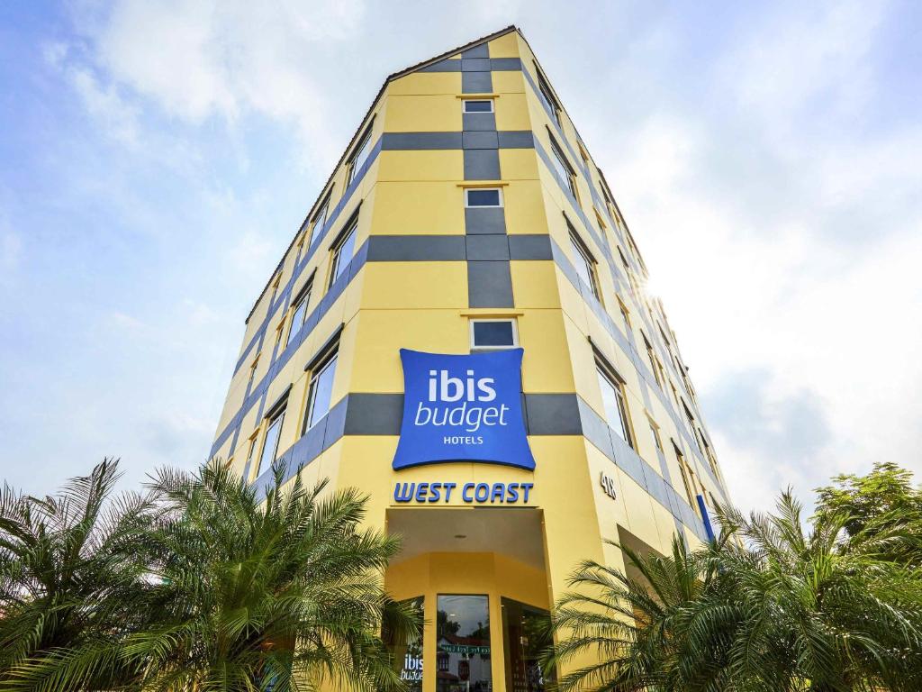 a tall yellow building with a blue sign on it at ibis budget Singapore West Coast in Singapore