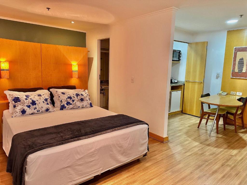 a bedroom with a bed and a table and a kitchen at Flat Itaim Bibi ar condicionado arrumação diária in Sao Paulo