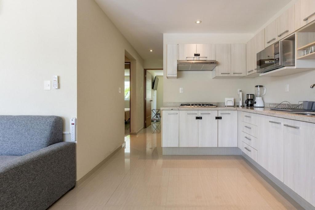 a kitchen with white cabinets and a blue couch at Residencial Diamante in Acapulco