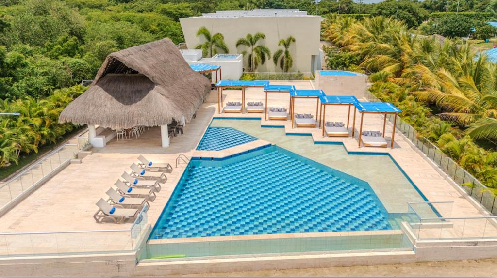 an aerial view of a resort pool with chairs and a thatch roof at Exclusiva casa en Baru con piscina y playa privada in Playa Blanca