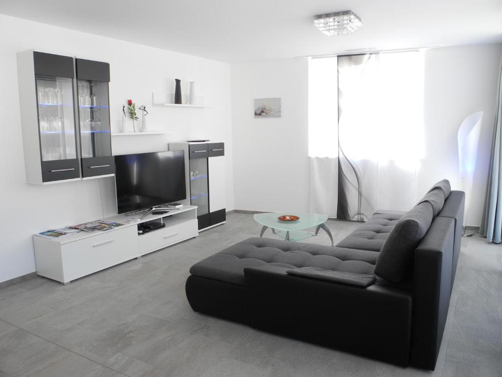 Brig City Apartment في بريغ: غرفة معيشة مع أريكة سوداء وتلفزيون