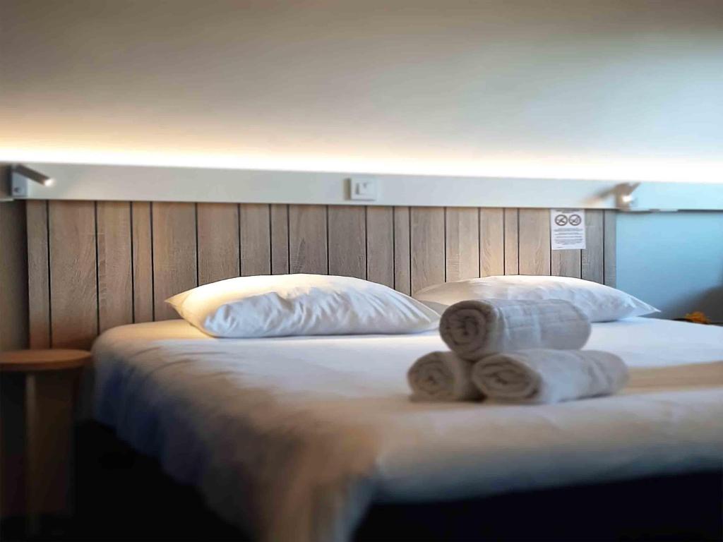 a bed with two rolls of towels on it at ibis Rennes Cesson in Cesson-Sévigné