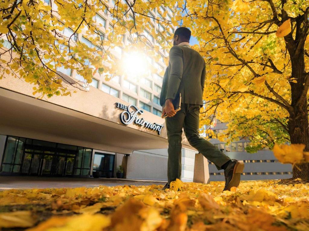 a man walking through leaves in front of a building at Fairmont Winnipeg in Winnipeg