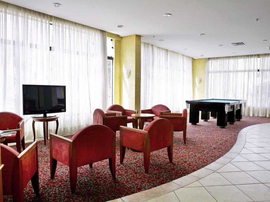 a waiting room with a tv and a table and chairs at ibis Taubate in Taubaté