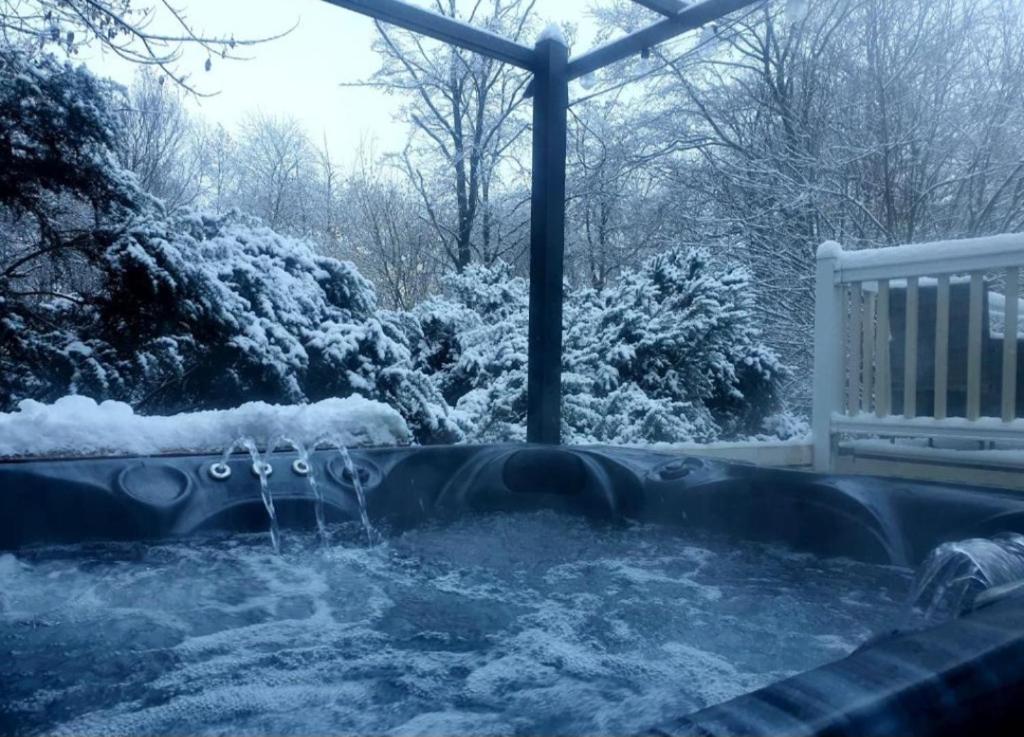 Un jacuzzi cubierto de nieve junto a un banco en The Treehouse Northumberland, en Swarland