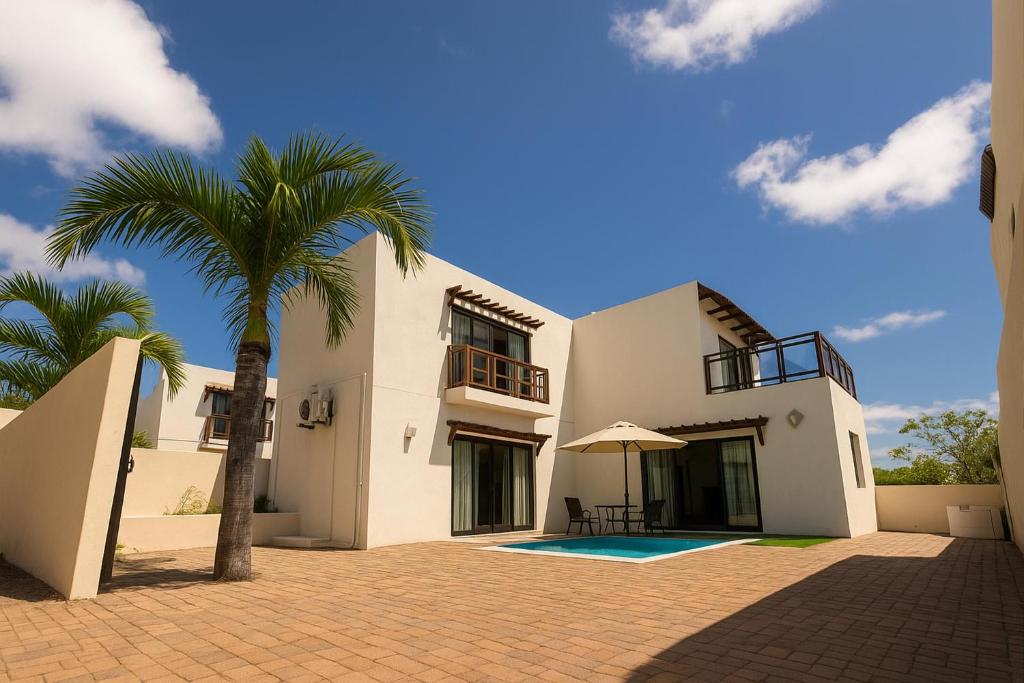 a white house with a palm tree in front of it at Hope Villa in Calodyne