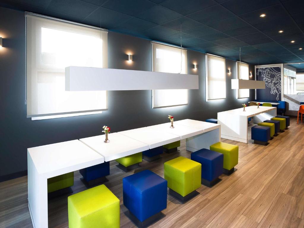 Una habitación con una mesa blanca y taburetes de colores. en Ibis Budget Madrid Alcorcón Móstoles, en Alcorcón
