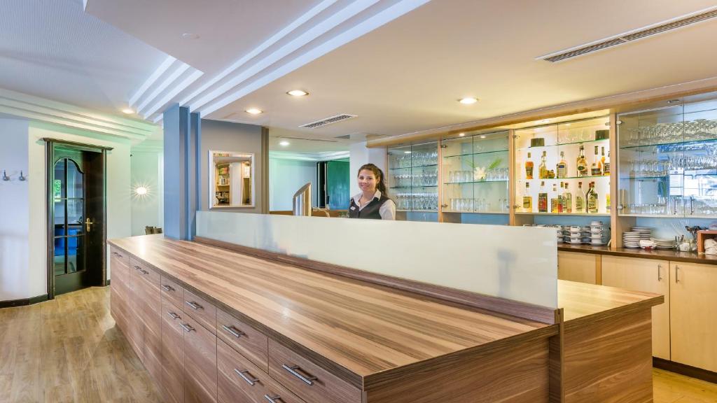 a woman standing behind a counter in a bar at Garner Hotel Stuttgart City Centre by IHG in Stuttgart