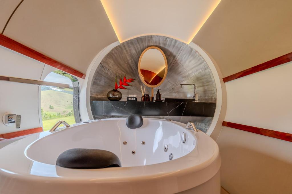 eine runde Badewanne in einem Raum mit einem runden Spiegel in der Unterkunft Pousada Aero Sofiste in Divino de São Lourenço