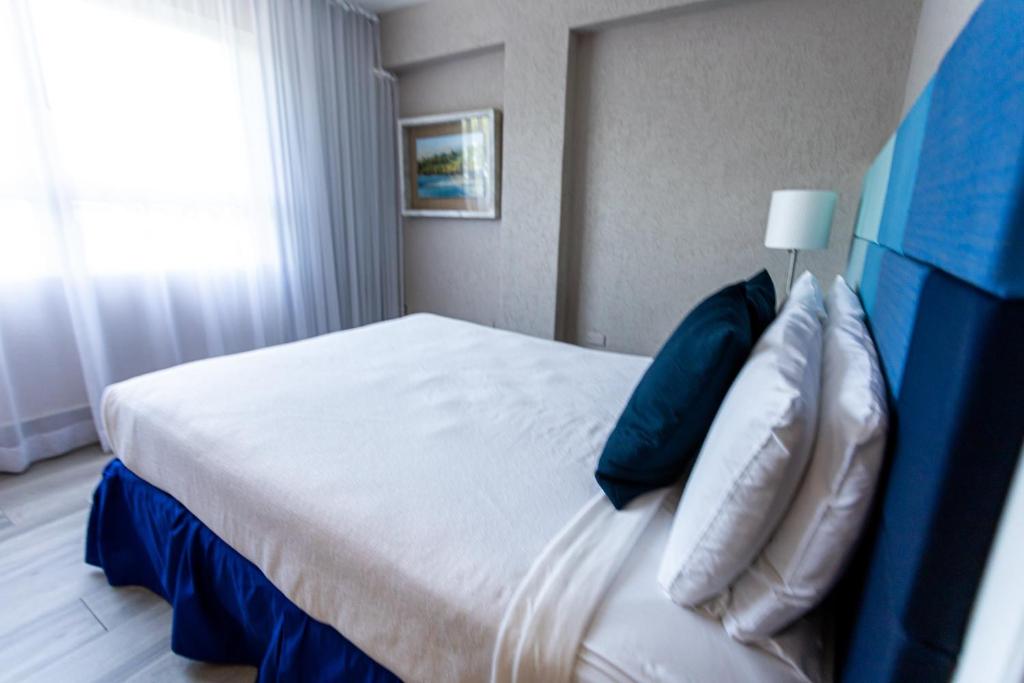 a bedroom with a white bed with blue pillows at The Wave Hotel Condado in San Juan