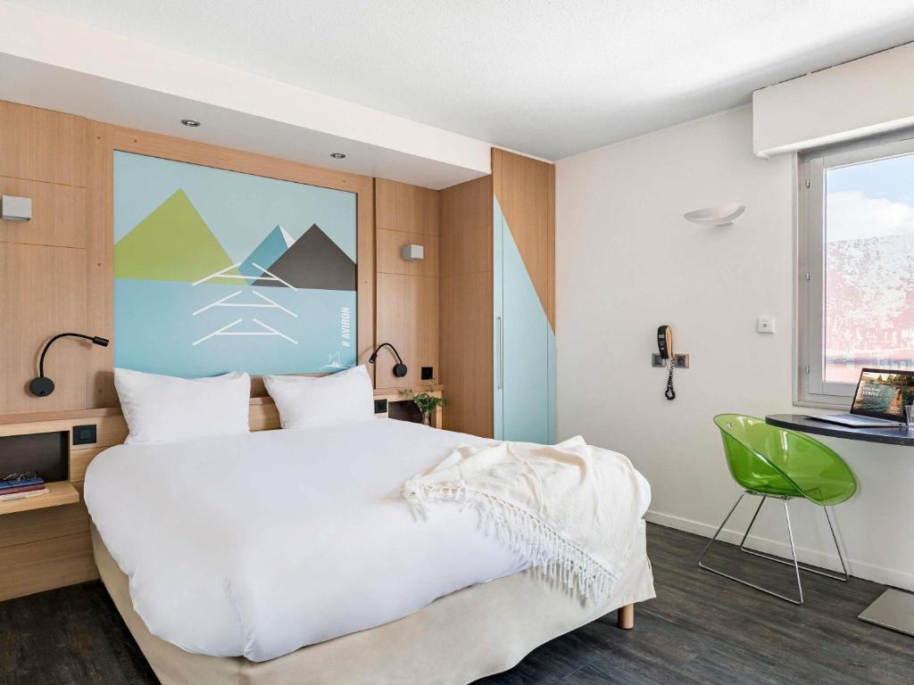 a bedroom with a large white bed and a green chair at ibis Styles Annecy Centre Gare in Annecy