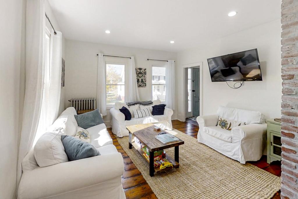 a living room with two white couches and a table at Boothbay Cottage in Boothbay Harbor