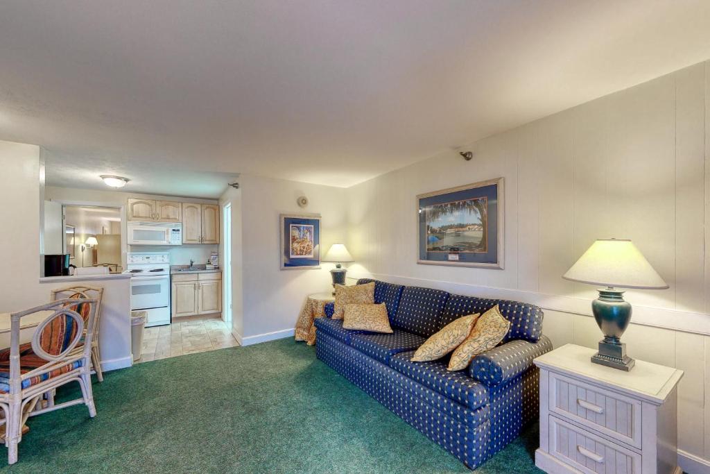 a living room with a blue couch and a kitchen at Seafarer Resort-Unit 107 in Ogunquit