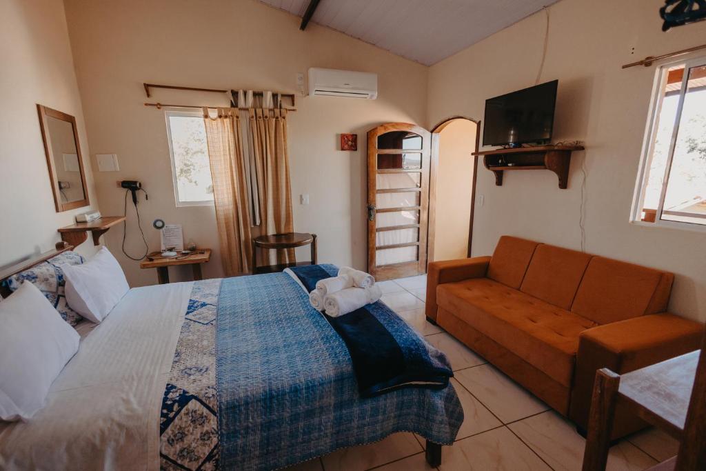 a bedroom with a bed and a couch at Pousada Casa do Cerrado - Alto Paraíso de Goiás in Alto Paraíso de Goiás